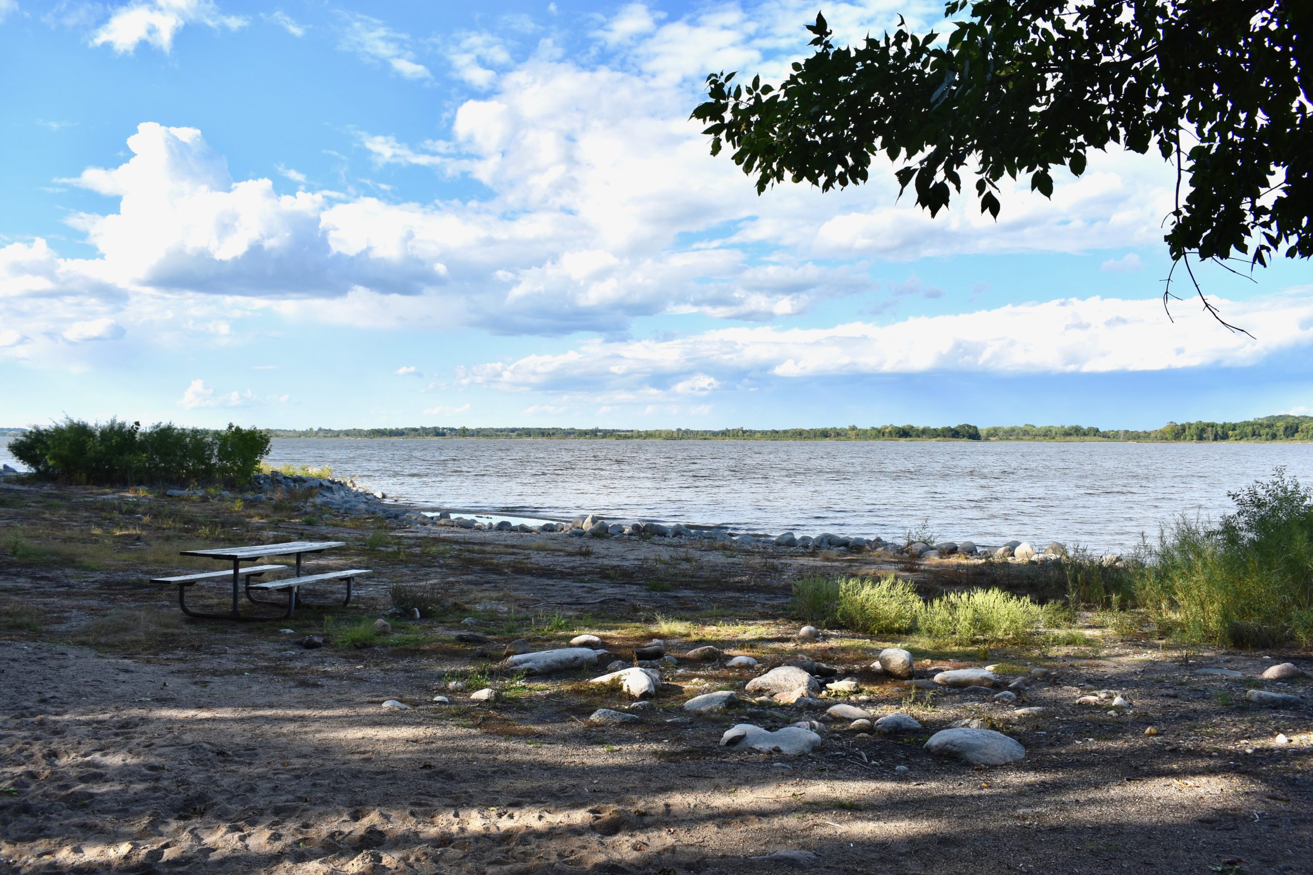 Lake in background. Picnic tables and fire pits in foreground.